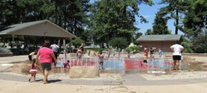 Children playing in the water jets of an outdoor splash pad on a hot summer day