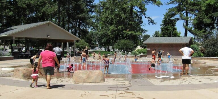 Children playing in the water jets of an outdoor splash pad on a hot summer day